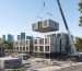Prefabricated modular building unit being installed by crane at an urban construction site in Australia